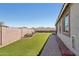 Well-maintained backyard with artificial turf, desert plants, and a paved walkway at 16521 W Magdalena Ln, Goodyear, AZ 85338