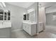 This bathroom has double sinks with white cabinets and gray walls with wood look tile flooring at 16521 W Magdalena Ln, Goodyear, AZ 85338