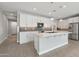 A modern kitchen is showcased with white cabinets, quartz countertops, stainless steel appliances and a kitchen island at 16521 W Magdalena Ln, Goodyear, AZ 85338