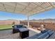 Inviting covered patio with stylish wicker furniture, a fire pit, and manicured landscaping at 16521 W Magdalena Ln, Goodyear, AZ 85338