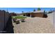 Backyard featuring gravel landscaping, a manicured lawn, covered patio, and mature trees offering outdoor enjoyment and low maintenance at 17415 N 57Th Ave, Glendale, AZ 85308