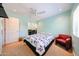 A light blue bedroom features a bed with black floral bedding, a red chair, a ceiling fan, and an adjacent work area at 17415 N 57Th Ave, Glendale, AZ 85308