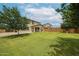 A beautiful, spacious backyard featuring well-maintained grass and lush trees against a backdrop of a sunny sky at 17681 W Molly Ln, Surprise, AZ 85387