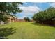 Vast backyard showcasing lush greenery, mature trees, and a glimpse of the home's architecture under a bright sky at 17681 W Molly Ln, Surprise, AZ 85387
