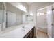 Well-lit bathroom showcasing a single sink vanity, large mirror, and a doorway to another space at 17681 W Molly Ln, Surprise, AZ 85387