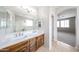 Bright bathroom featuring double sinks, a large mirror, and a separate shower, with bedroom view at 17681 W Molly Ln, Surprise, AZ 85387