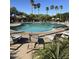 Resort-style community pool with lounge chairs, palm trees, and shaded seating areas for relaxation and recreation at 17681 W Molly Ln, Surprise, AZ 85387