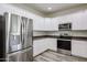 Well-lit kitchen features stainless steel appliances, granite counters and ample white cabinetry at 17681 W Molly Ln, Surprise, AZ 85387
