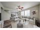 Well-lit living room featuring plush white seating, wood-look floors, and a view into the kitchen at 17681 W Molly Ln, Surprise, AZ 85387