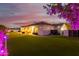 Evening view of the house with manicured lawn, covered patio, and tasteful backyard lighting at 18226 W Marshall Ct, Litchfield Park, AZ 85340