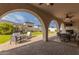 Stunning covered patio with travertine flooring, seating area, and outdoor dining with view of lush landscaping at 18226 W Marshall Ct, Litchfield Park, AZ 85340
