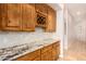 A butlers pantry with wood cabinets, wine rack, granite countertops and a view to the hallway at 18226 W Marshall Ct, Litchfield Park, AZ 85340