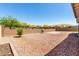 This gravel backyard includes mature trees and a retaining wall at 18508 W Galveston St, Goodyear, AZ 85338