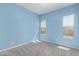 Bright blue bedroom featuring neutral carpeting, two windows and freshly painted walls at 18508 W Galveston St, Goodyear, AZ 85338