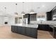 Modern kitchen boasts granite countertops, dark cabinetry, stainless steel appliances and pendant lighting over the island at 19622 W Pasadena Ave, Litchfield Park, AZ 85340