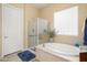 Bright bathroom with a soaking tub, glass shower, and neutral tile flooring at 20140 N 269Th Dr, Buckeye, AZ 85396