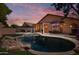 Relaxing backyard with a sparkling pool, rock waterfall feature, dining area, and lush greenery at 2236 E Rawhide St, Gilbert, AZ 85296