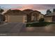 Charming single-story home with a two-car garage, well-manicured lawn, and desert landscaping at sunset at 2236 E Rawhide St, Gilbert, AZ 85296