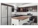 Updated kitchen featuring a stainless steel refrigerator, dark cabinetry, island, and granite countertops at 2236 E Rawhide St, Gilbert, AZ 85296