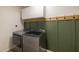 Well-equipped laundry room featuring modern washer and dryer, cabinets, and stylish olive green accent wall at 300 E Moore Ave, Gilbert, AZ 85234