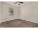 Neutral bedroom showcasing carpet, a window with tree views, and ceiling fan at 30003 W Rockmount Ave, Buckeye, AZ 85396