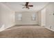Bright living room featuring neutral paint, plush carpeting, and a ceiling fan for comfort at 30003 W Rockmount Ave, Buckeye, AZ 85396