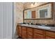 Bathroom featuring double sinks, wood cabinets, decorative wall texture, and a large mirror at 3203 E Ellis St, Mesa, AZ 85213
