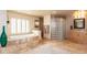 A luxurious main bathroom with a large soaking tub, glass block shower, and dual vanities at 3522 E Cherokee St, Phoenix, AZ 85044