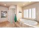 A luxurious main bathroom with a soaking tub, glass block shower, and tiled flooring at 3522 E Cherokee St, Phoenix, AZ 85044