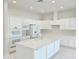 This modern kitchen features white cabinetry, appliances, an island with sink, and white tile flooring at 3780 E Rakestraw Ln, Gilbert, AZ 85298