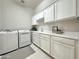 Well-lit laundry room with washer, dryer, white cabinetry, countertop, sink and tile floors at 3780 E Rakestraw Ln, Gilbert, AZ 85298