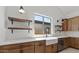 Bright kitchen with wood cabinets, quartz countertops, floating shelves, and a farmhouse-style sink with modern faucet at 537 E Aurora Dr, San Tan Valley, AZ 85140