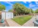 Large, landscaped backyard with green grass, paved walkway, storage shed, and privacy fencing at 616 E Sheffield Ave, Gilbert, AZ 85296
