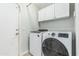 Bright laundry room featuring a white washer and dryer set with overhead cabinets for ample storage at 6422 W Range Mule Dr, Phoenix, AZ 85083