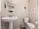 Cozy half bathroom with a pedestal sink, toilet, and decorative wall art at 8244 W Albeniz Pl, Phoenix, AZ 85043