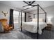 Stylish bedroom showcasing a four-poster bed, a rocking chair, and a large sunny window at 9052 E Hobart St, Mesa, AZ 85207