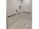 Bright and accessible shower, featuring grab bars and textured tile floor for added safety at 11074 W Tonto St, Avondale, AZ 85323