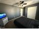 Bedroom with carpeted floor features a black bed, ceiling fan, and a wall-mounted TV at 11644 W Redfield Rd, El Mirage, AZ 85335
