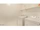 Laundry room features a white washer and dryer with overhead shelving for storage at 11644 W Redfield Rd, El Mirage, AZ 85335