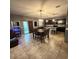 Open-concept living and dining area with tile floors, modern light fixture, and kitchen in background at 11644 W Redfield Rd, El Mirage, AZ 85335