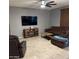 Comfortable living room features tile floors, a large TV, and brown sofas with coffee table at 11644 W Redfield Rd, El Mirage, AZ 85335
