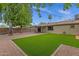 Serene backyard featuring an artificial turf lawn, mature trees, and a covered patio at 14215 N 36Th Way, Phoenix, AZ 85032