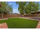 Expansive backyard featuring artificial turf lawn, mature trees, and brick-lined landscaping at 14215 N 36Th Way, Phoenix, AZ 85032