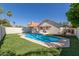 View of the backyard pool with a privacy fence, grassy yard, and view of the back of the home at 1425 E Commerce Ave, Gilbert, AZ 85234