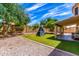 Landscaped backyard with artificial grass, climbing toy, rock area, and a covered patio at 1631 N Avoca --, Mesa, AZ 85207