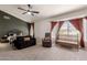 Spacious bedroom with a dark accent wall, a ceiling fan, and large windows with rust-colored drapes at 1631 N Avoca --, Mesa, AZ 85207