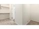 Open walk-in closet with white shelving and carpet, and entryway to bathroom at 25221 N 131St Dr, Peoria, AZ 85383