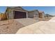 Attached garage features a dark brown door, stone driveway, desert landscaping, and taupe stucco at 25319 N 131St Dr, Peoria, AZ 85383