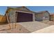 Attached garage features a dark brown door, stone driveway, desert landscaping, and taupe stucco at 25319 N 131St Dr, Peoria, AZ 85383