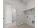 Bright laundry room with neutral tile flooring, a storage shelf, and doorway to a bathroom at 25319 N 131St Dr, Peoria, AZ 85383